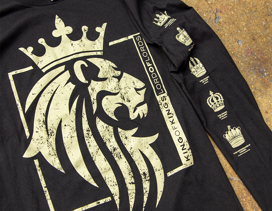 Black long sleeve shirt with large distressed gold lion graphic on the front and multiple crown illustrations printed down the sleeve.