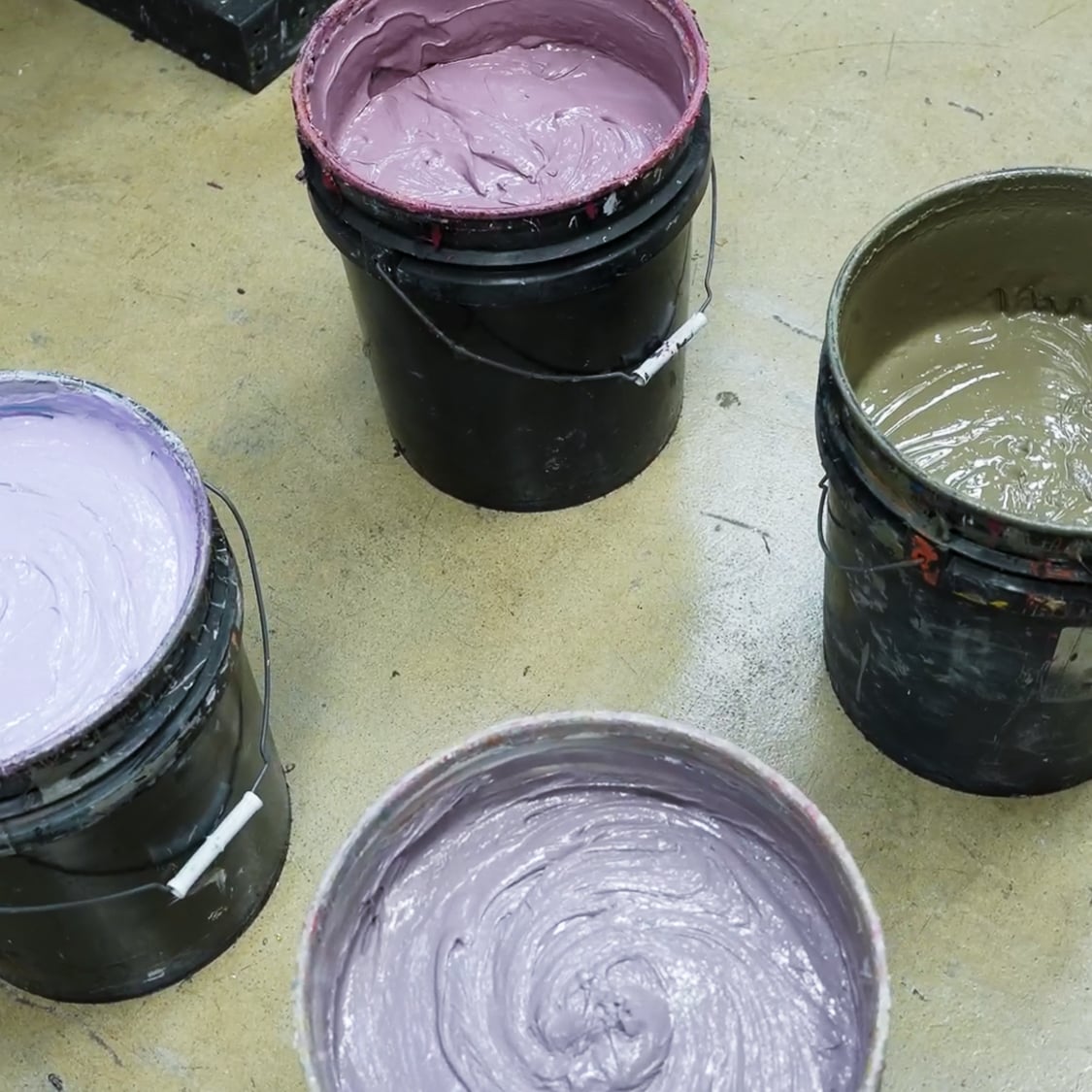 Buckets of mixed upcycling screen printing inks in shades of lavender mauve and earthy tones prepared for upcycled apparel printing at Hittn Skins