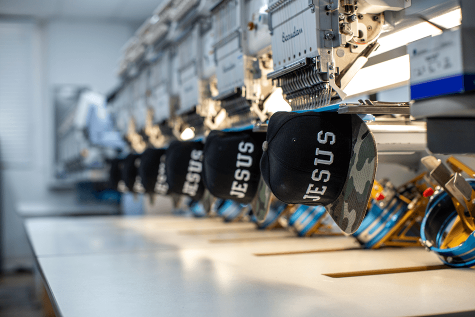 Jesus Logo being embroidered on snapback hats using Barudan Embroidery Machinery 
