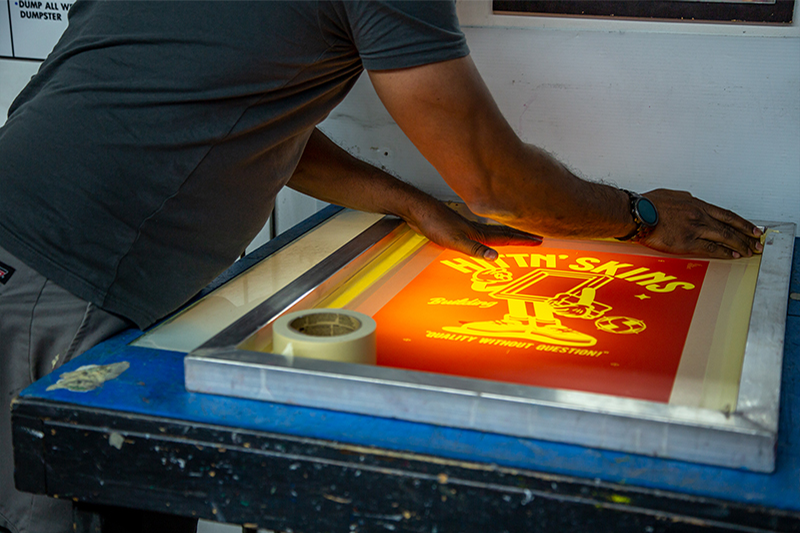 Production Helper Taping Down Screen at Hittn' Skins