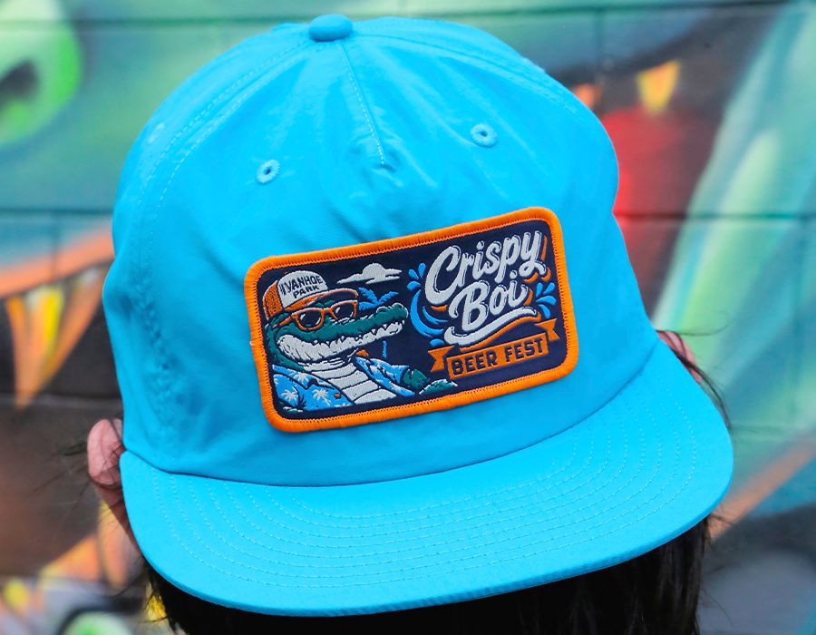 Custom surf hat for Crispy Bois Beer Fest featuring a large multicolor embroidered patch with detailed artwork and merrowed border.