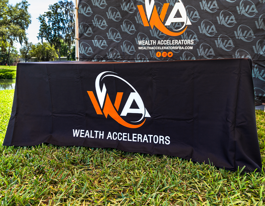 Custom black table cover for Wealth Accelerators with large orange and white logo branding for trade shows, conferences and corporate events.