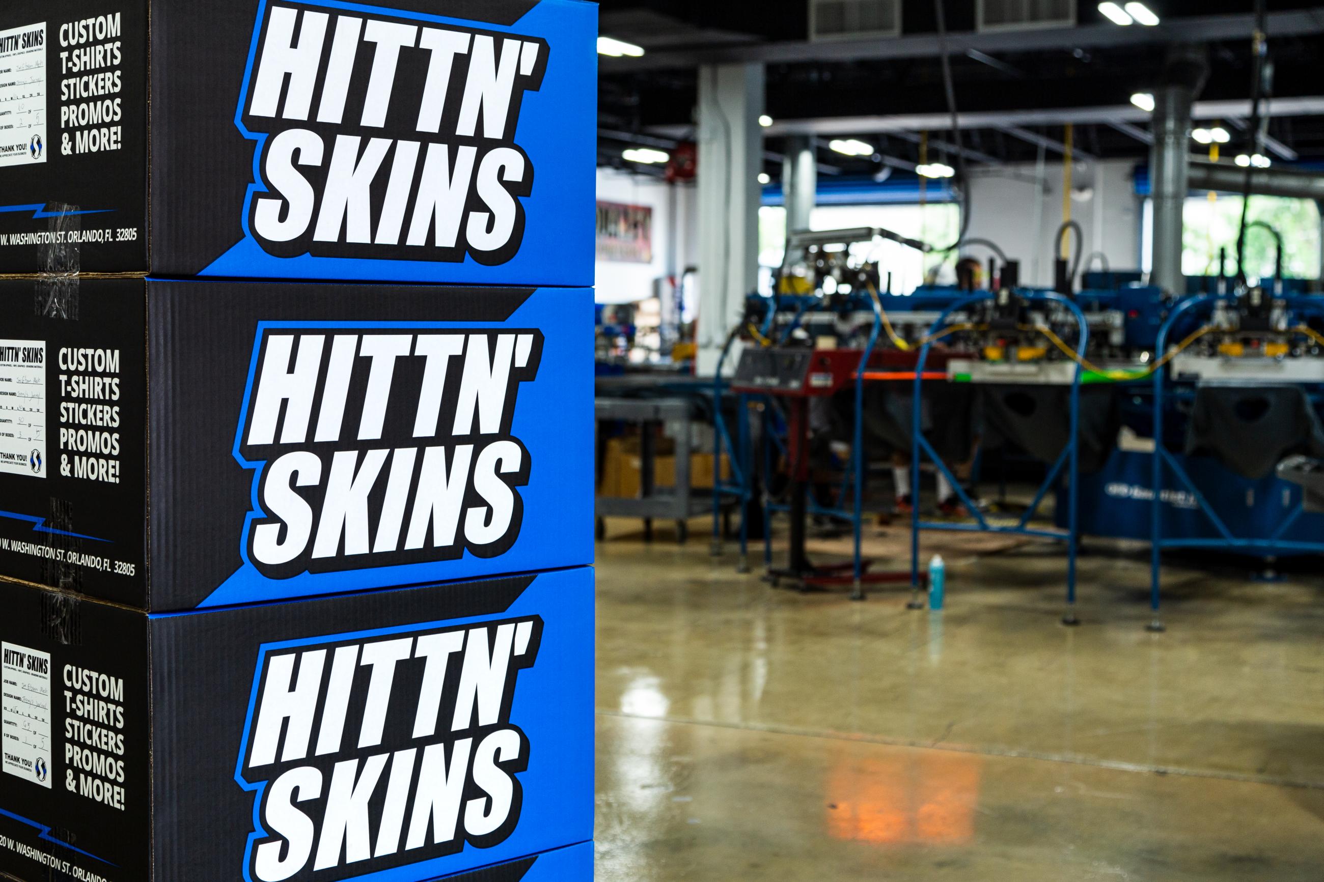 Hittn' Skins packaging stacked in front of M&R Screen Printing machine. 